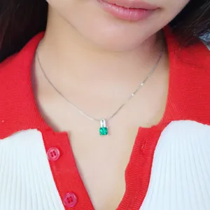 Nahaufnahme Detail der eleganten quadratischen grünen Edelsteinkette am Hals des Modells.