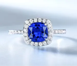 Detaillierte Nahaufnahme eines silbernen Kissen blauen Edelsteinrings mit Halo Diamanten.