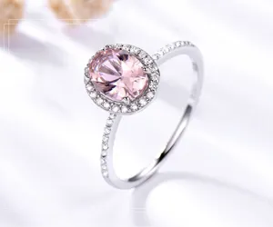Detaillierte Nahaufnahme des eleganten ovalen rosa Edelsteinrings mit funkelndem Halo-Design.