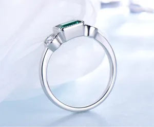 Detailansicht eines S925 Silberrings mit grünem Smaragdschliff Stein und klaren Seitensteinen.