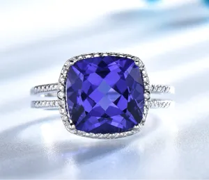 Primo piano dettaglio dell'anello in tanzanite blu taglio cuscino con diamanti in argento.