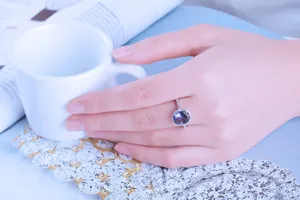 Vista dettagliata di un anello in argento 925 con gemma ovale blu viola su mano.