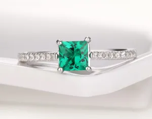 Detailaufnahme eines quadratischen grünen Edelsteinrings mit funkelnden Zirkoniasteinen.
