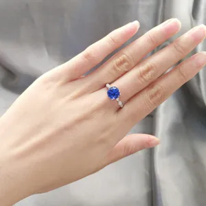 Nahaufnahme des silbernen Rings mit rundem blauen Edelstein und zarten Seitensteinen