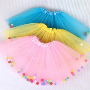 Close-up detail of colorful children tulle tutus with small pom-poms for stage performance.