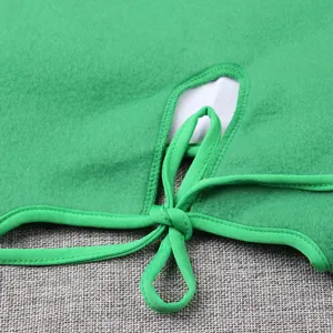 Green Christmas costume detail close up, soft fleece fabric with neat stitching and ribbon tie.