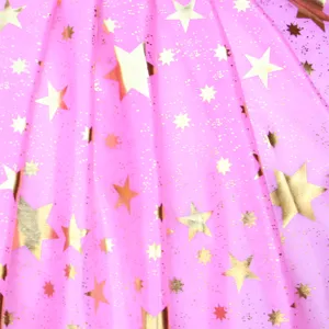 Gros plan sur un tissu en maille rose avec des étoiles dorées pour cape de costume d'Halloween.