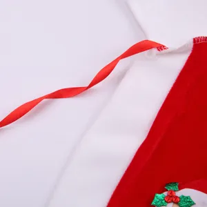 Kids Christmas Santa costume detail red velvet fabric with ribbon and festive holly decor.
