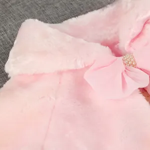 Détail de cape en fausse fourrure rose, nœud en mousseline et perle pour fête d'hiver.