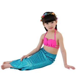 Kids mermaid swimsuit set with pink seashell bikini top, blue scale tail skirt and floral wreath.
