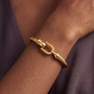 Gold cable twist bracelet with horseshoe U-buckle clasp minimalist luxury jewelry accessory.