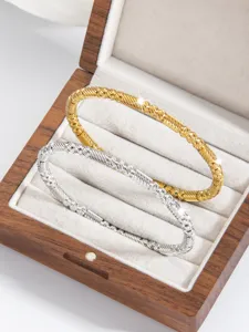 Nahaufnahme von luxuriösen goldenen und silbernen tordierten edelstahl armreifen für damen.