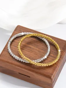 Nahaufnahme von silbernen und goldenen strukturierten Perlenarmbändern mit feinen Mustern.