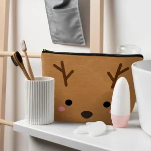 Primer plano de un neceser de lino con estampado de reno sobre un tocador de baño limpio.