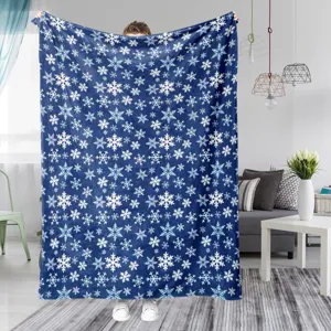 Cozy flannel fleece blanket with white snowflake pattern, displayed in a warm living room.