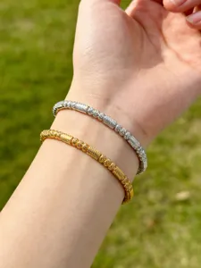 Nahaufnahme Detail von gold- und silberfarbenen gedrehten Kabel-Armbändern am Handgelenk.