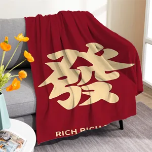 Vista detallada de la elegante manta de felpa roja con caracteres chinos dorados.