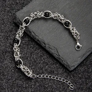 Close-up of stainless steel black bead woven chain bracelet, detailed metallic texture.