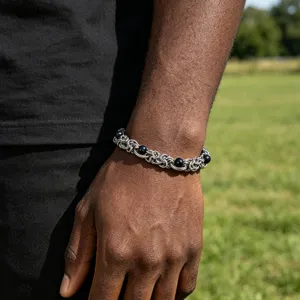Close-up detail shot of stainless steel chain bracelet featuring black beads worn on wrist.