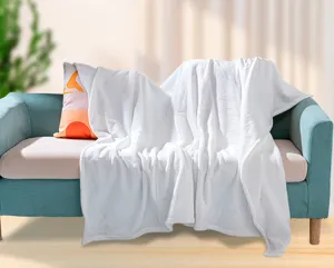 Dettaglio di coperta in flanella bianca morbida su divano turchese in ambiente moderno.