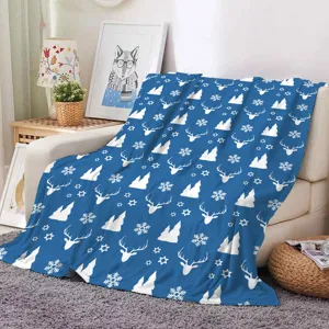 Detailed view of cozy blue Christmas flannel blanket with white deer and snowflake patterns.