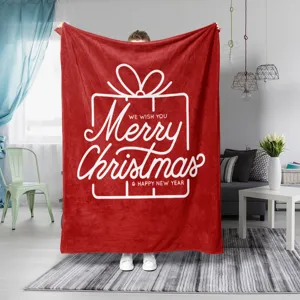 Vista detallada de la manta navideña de felpa roja con gráficos festivos blancos para el hogar.