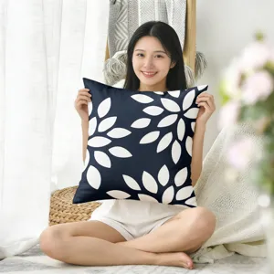 Gros plan d'une housse de coussin bleu marine à motif de feuilles dans une pièce chaleureuse.