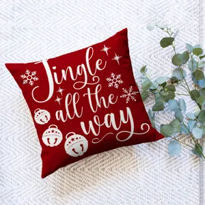Detail view of a red Christmas decorative throw pillow cover with festive white holiday text.