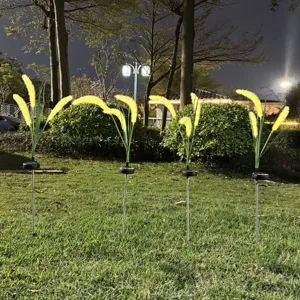 Detail view of LED solar foxtail grass light glowing warmly on outdoor lawn at night.