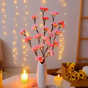 Gros plan de la lampe branche de cerisier LED en vase céramique blanc, décor chaleureux.
