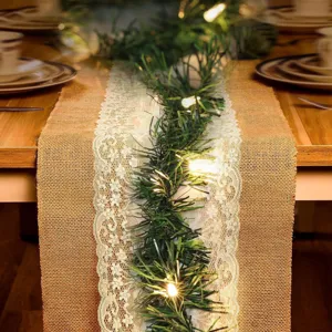 Chemin de table en jute de Noël avec guirlande de pin vert et lumières LED de fête.