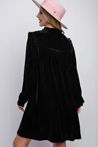 Detalle de vestido negro de terciopelo de manga larga, mostrando textura suave y diseño.