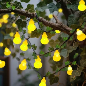 Detailed view of solar gourd string lights with green leaves for garden balcony and home decor.