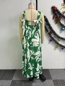 Detail view of the green sleeveless maxi dress showcasing white leaf print and bow straps.