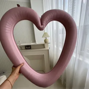 Close-up of a large dusty pink heart-shaped foil balloon photo frame held by hand