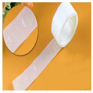 Close-up detail of clear double-sided balloon glue dots roll on orange background.