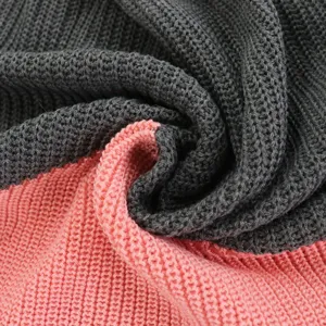 Close-up detail of soft color-block knit fabric texture, showing grey and pink ribbed knit.