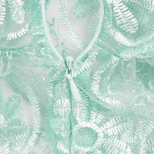 Mint green lace dress detail close-up showing delicate floral embroidery and matching zipper.