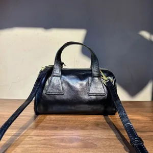 Détail sac Boston en cuir, texture noire vintage, fermeture éclair et bandoulière.