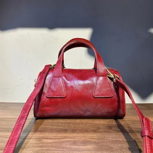 Vue detaillee du sac Boston en cuir de vachette retro rouge fonce avec poignees et metal dore.