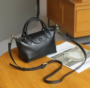 Detail shot of black genuine leather mini tote bag, retro shoulder bag with crossbody strap.