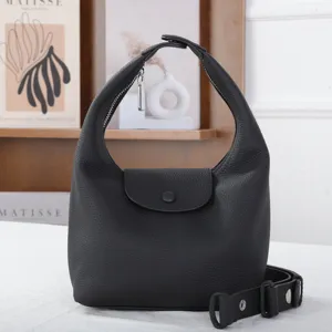 Vue détaillée du sac porté épaule noir en cuir véritable avec son rabat élégant et lanière.
