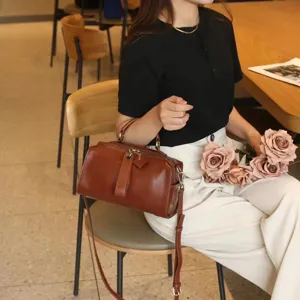 Vintage genuine leather pillow bag for women, stylish brown shoulder handbag with top handle.