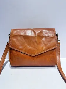 Retro brown leather crossbody bag detail, vintage envelope flap style with bronze hardware.