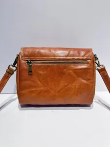 Vintage genuine leather crossbody bag detail, brown leather texture with durable metal zippers.