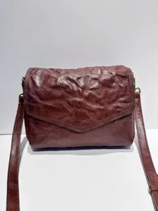 Close-up detail of retro crinkled leather crossbody bag texture and envelope flap design.