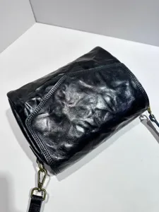 Close-up of black genuine leather vintage envelope crossbody bag with detailed crinkled texture.