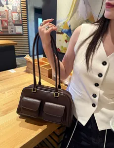 Borsa a tracolla in pelle marrone con doppi manici e due tasche frontali, design casual.