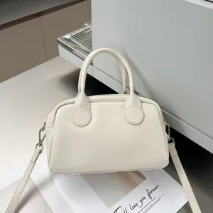Detail view of creamy white soft cowhide Boston bag showing pebble texture and sturdy handles.