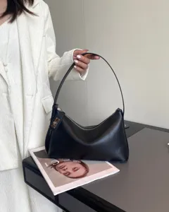 Detail view of a black leather underarm shoulder bag, elegant crescent hobo style.